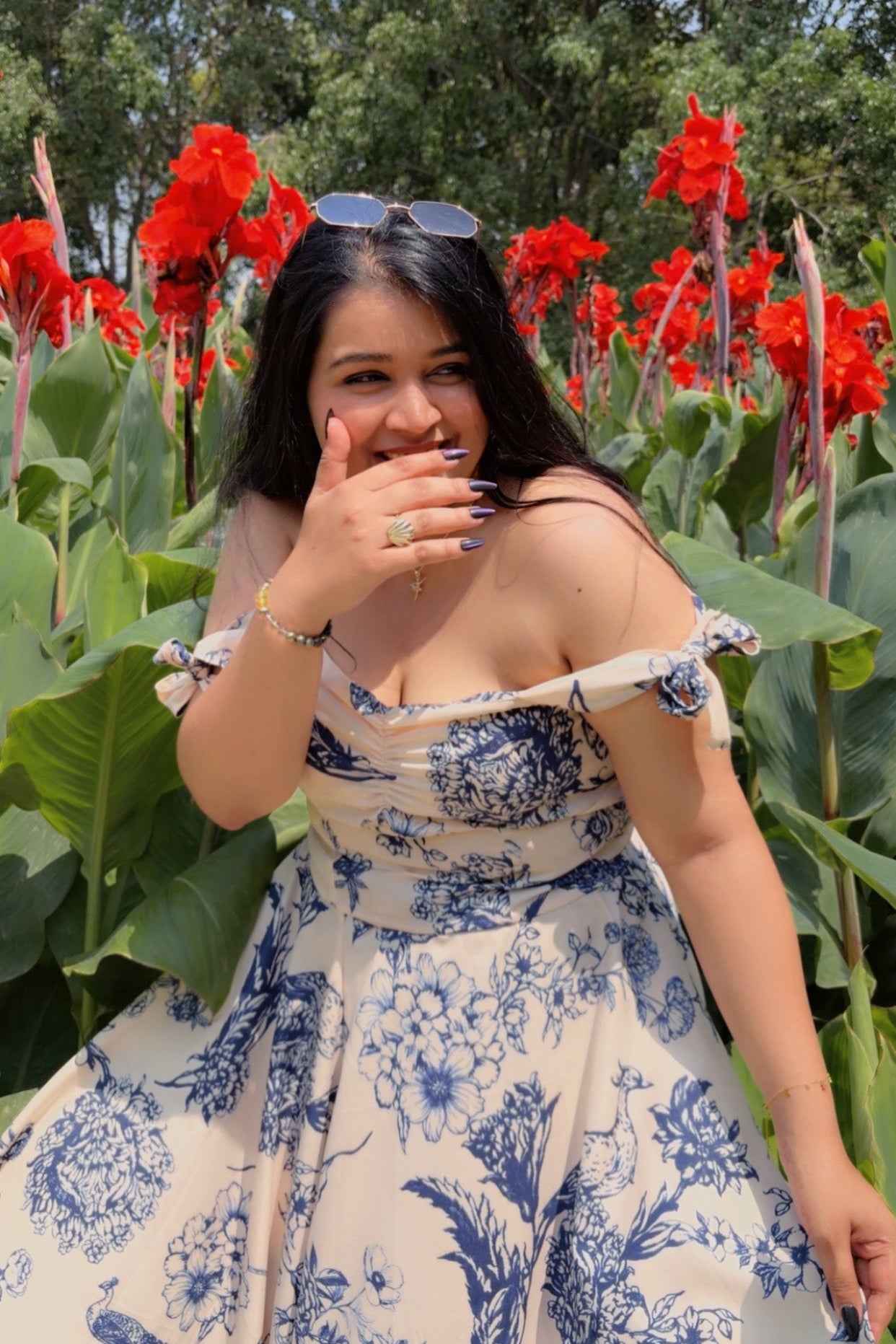 Woman in a floral dress standing in a field of red flowers