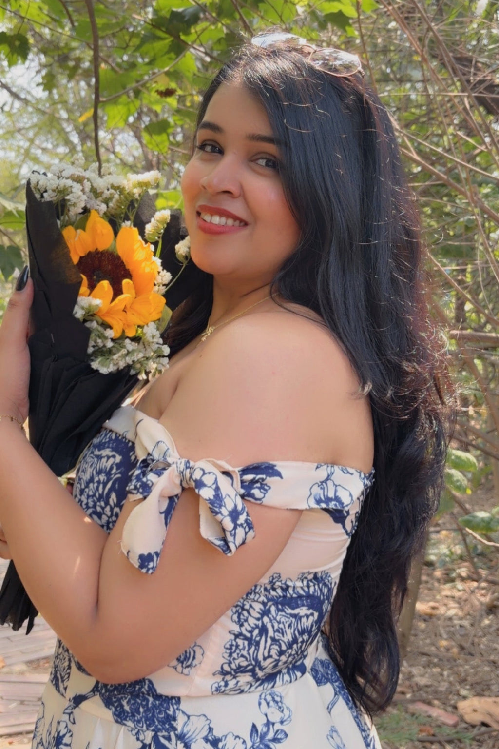 Woman in a floral dress holding a bouquet of flowers outdoors