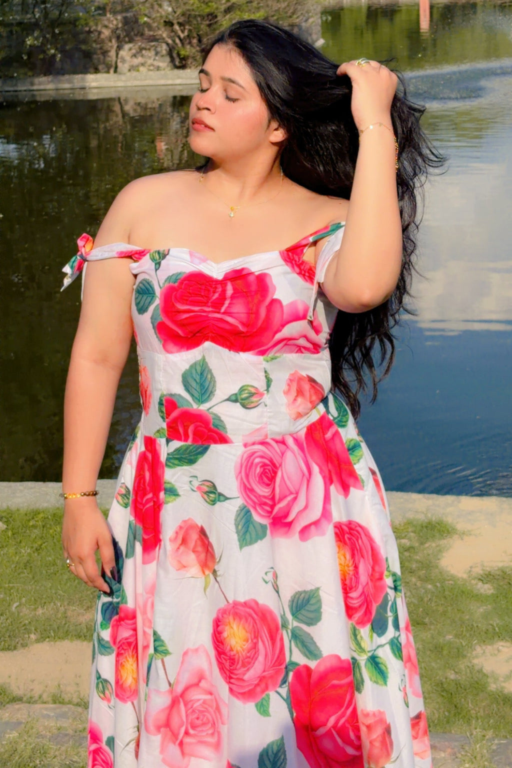Woman in a floral dress standing by a lake