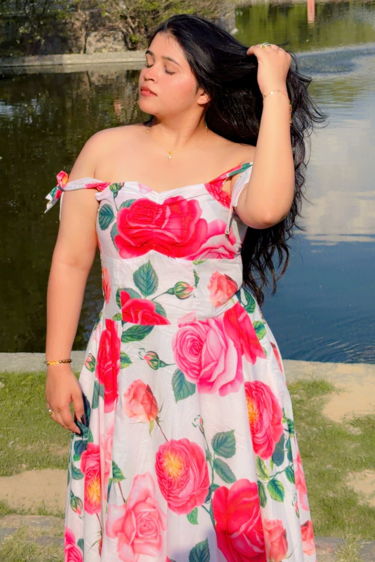 Woman in a floral dress standing by a lake