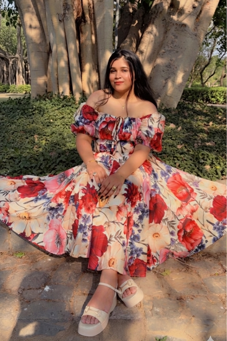 Woman in a floral dress sitting under a large tree