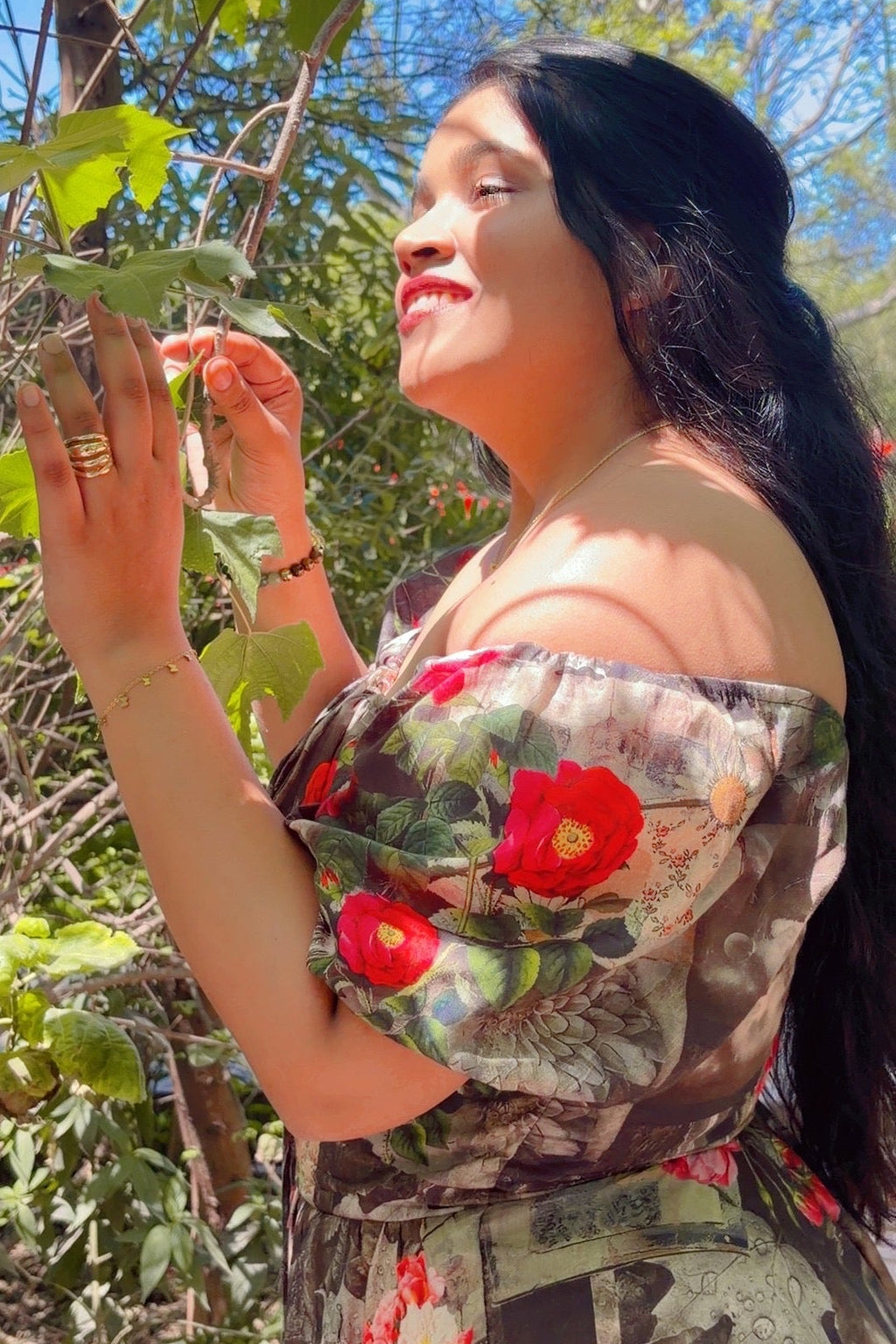 Woman in a floral dress standing outdoors with greenery around