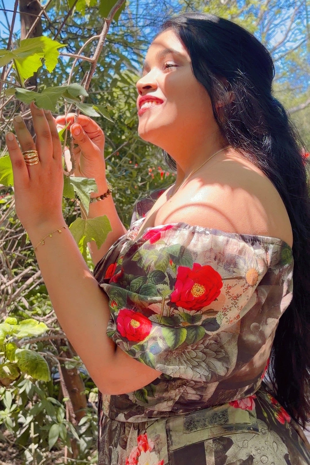 Woman in a floral dress standing outdoors with greenery around