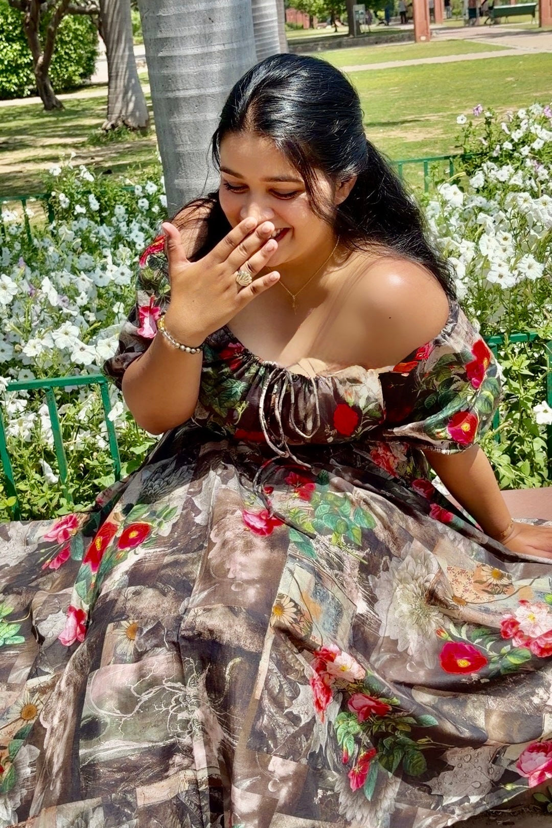 Woman in a floral dress sitting on a bench in a park